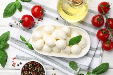 Lezzetli mozzarella peyniri, domates, fesleğen ve baharatlar beyaz ahşap masa üzerinde, düz yatıyordu.