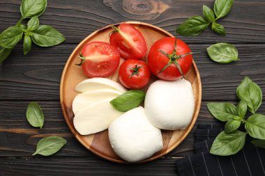Lezzetli mozzarella peyniri, domates ve fesleğen, ahşap masa, düz uzanma