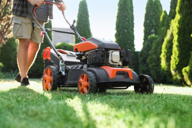 Bahçede çim biçme makinesiyle çimen biçen adam, yakın plan.