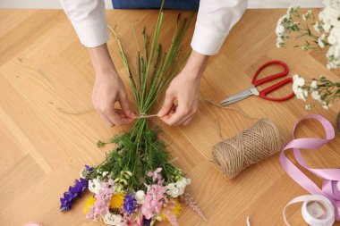 Çiçek buketi yapan bir çiçekçi, ahşap masa, üst manzara