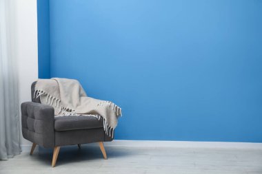 İçeride mavi duvarın yanında ekoseli rahat bir koltuk. Metin için boşluk