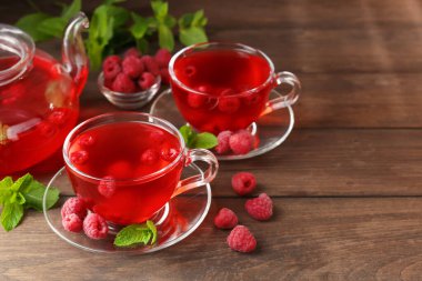 Cam bardaklarda ahududu çayı, çaydanlık, böğürtlen ve nane şekeri ahşap masada, yakın plan. Metin için boşluk