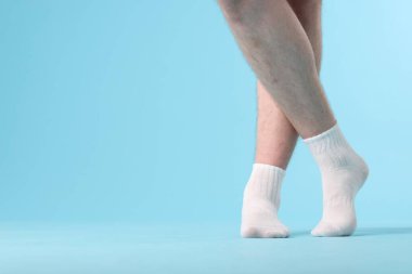 Açık mavi arka planda temiz beyaz çorap giyen adam, yakın plan. Metin için boşluk