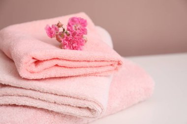 Yumuşak havlu ve çiçekler beyaz masanın üzerinde, yakın plan. Metin için boşluk