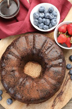 Lezzetli çikolatalı kek, çilek ve böğürtlen ahşap masada, düz uzanmış