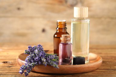 Ahşap masada lavanta şişeleri ve çiçekler, yakın plan.