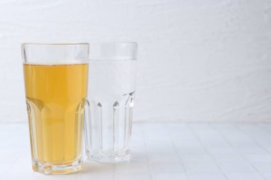 Temiz ve kirli su bardakları beyaz fayanslı masada, yakın plan. Metin için boşluk