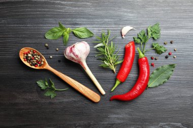 Farklı aromatik otlar, ürünler ve siyah ahşap masa üzerinde biber ve kaşık düz yatıyordu.