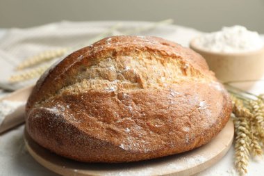 Bir somun taze ekmek, un ve çiviler masada, yakın plan.