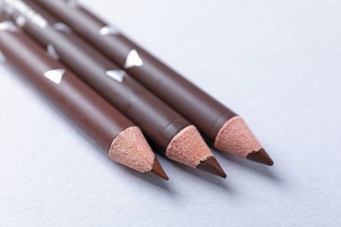 Beyaz arka planda üç kaş kalemi, yakın plan.