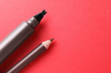 Kırmızı arka planda farklı kaş kalemleri, yakın plan. Metin için boşluk