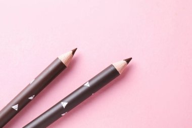 Pembe arka planda kaş kalemleri, üst tarafta. Metin için boşluk
