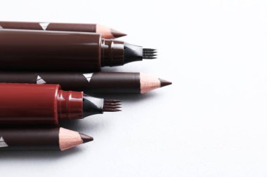 Beyaz arka planda farklı kaş kalemleri, yakın plan. Metin için boşluk