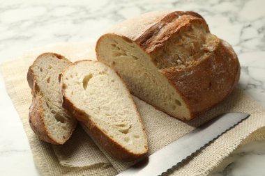 Beyaz mermer masada taze ekmek ve bıçak parçaları, yakın plan.