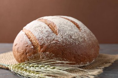 Taze ekmek ve yeşil buğday çivileri ahşap masada, yakın plan.