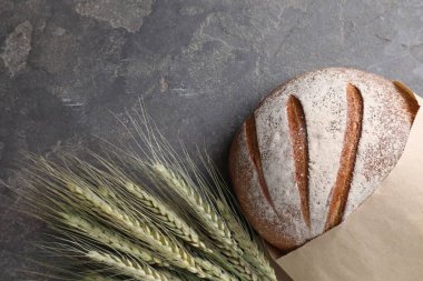 Taze ekmek ve yeşil buğday çivileri gri masada, düz yerde.