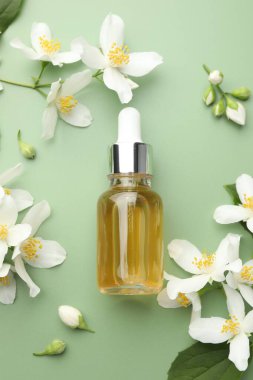 Yağ ve yasemin çiçekleri yeşil arka planda düzdür.