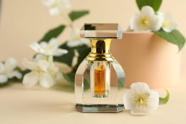 Bir şişe parfüm ve bej arka planda yasemin çiçekleri, yakın plan.