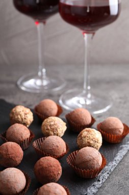 Lezzetli yer mantarı bonbonları ve gri desenli masada kırmızı şarap, yakın plan.