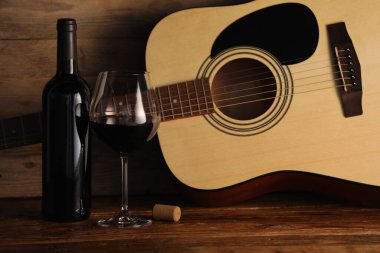 Akustik gitar, şişe ve bir bardak kırmızı şarap.