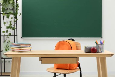 Farklı okul kırtasiyesi ve kırmızı elma, kapalı alanda tahtaya yakın ahşap masada.