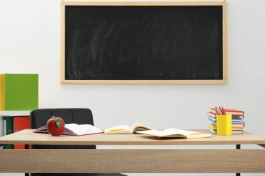 Farklı kırtasiye malzemesi ve kırmızı elma, kapalı alanda, tahtanın yanında.