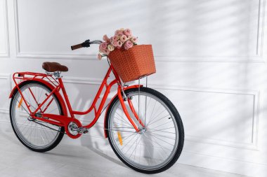 Beyaz duvarın yanında güzel çiçeklerle dolu bir bisiklet. Metin için boşluk