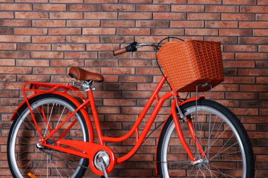 İçeride tuğla duvarın yanında sepeti olan kırmızı bisiklet.