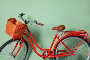 Açık yeşil duvarın yanında sepeti olan kırmızı bisiklet, yakın plan.