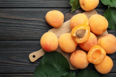 Taze kayısılar ve yeşil yapraklar koyu ahşap masada, düz yerde. Metin için boşluk