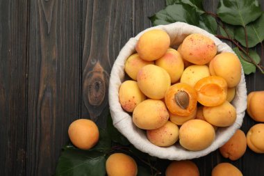 Taze kayısılar ve yeşil yapraklar koyu ahşap masada, düz yerde. Metin için boşluk