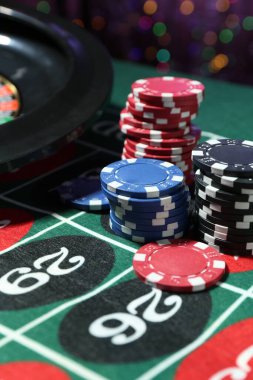 Kumarhane fişleri ve rulet masası bulanık ışıklara karşı, yakın plan.