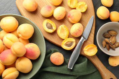 Taze kayısılar, çekirdekler ve bıçak siyah masada, düz yerde.