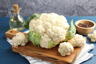 Çiğ karnabahar, biber ve yağ mavi ahşap masada.