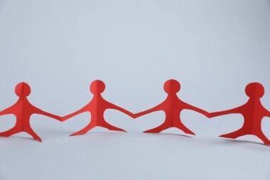 Işık arkaplanda el ele tutuşan insan kağıt figürleri