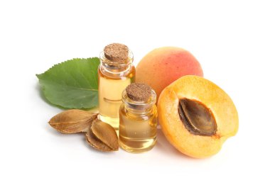 Beyaz üzerine izole edilmiş yağ şişeleri, taze kayısılar, çekirdekler ve yeşil yaprak.