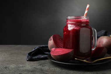 Süper yemek. Mason kavanozunda smoothie ve gri desenli masada pancar kökü koyu arka planda, yakın plan. Metin için boşluk