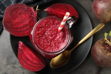 Süper yemek. Mason kavanozunda meyve püresi ve gri desenli masa üzerinde pancar kökü.