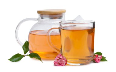 Cam fincanda Aromatik çay, çaydanlık, güller ve yeşil yapraklar beyaz üzerine izole edilmiş.