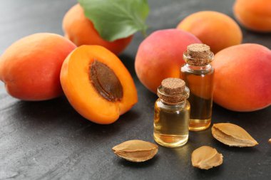 Şişelerde, tohumlarda ve olgun kayısılarda koyu dokulu masalarda, yakın çekim.