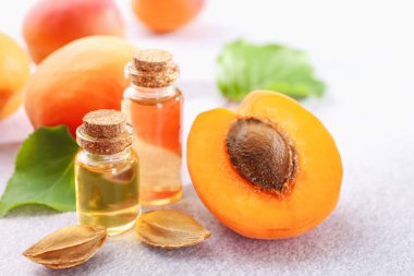 Şişelerdeki, tohumlardaki ve olgun kayısılardaki yağlar açık dokulu masalarda, yakın çekim.