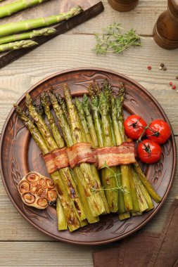 Lezzetli pişmiş kuşkonmaz, domuz pastırması ve baharatla servis edilir.