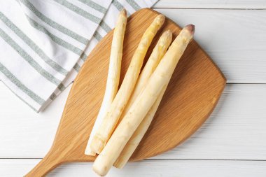 Beyaz ahşap masada çiğ kuşkonmaz mızrakları.