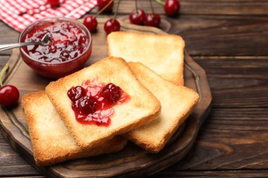 Lezzetli kiraz reçelli tostlar ve ahşap masada taze meyveler, yakın plan.