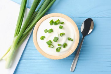 Taze soğanlı lezzetli yoğurt açık mavi ahşap masa, düz uzanmış
