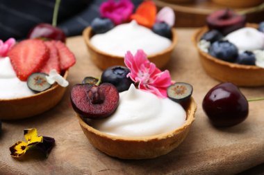 Masada böğürtlenli ve çiçekli tartlar, yakın plan. Tatlı nefis.