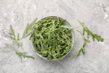 Taze, yeşil roka yaprakları kasede gri masada, düz yatıyordu.