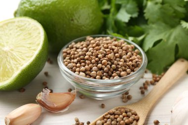 Kişniş çekirdeği, taze kişniş, kireç ve sarımsak açık ahşap masa, yakın plan.