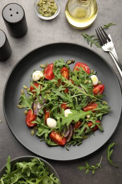 Lezzetli salata roka, mozzarella ve sebzeler gri masada servis edilir.