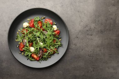 Lezzetli salata roka, mozzarella ve gri masada sebzeler, üst manzara. Metin için boşluk